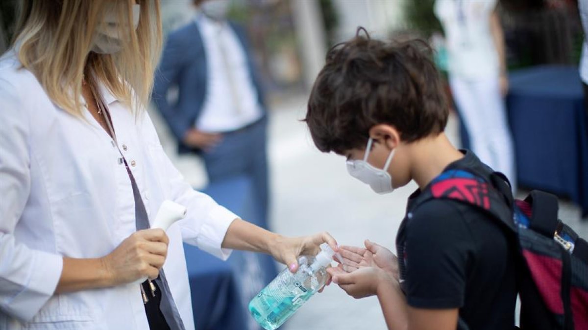 Un nen es desinfecta les mans després que li prenguin la temperatura a l'entrada del col·legi privat internacional American School of Barcelona.