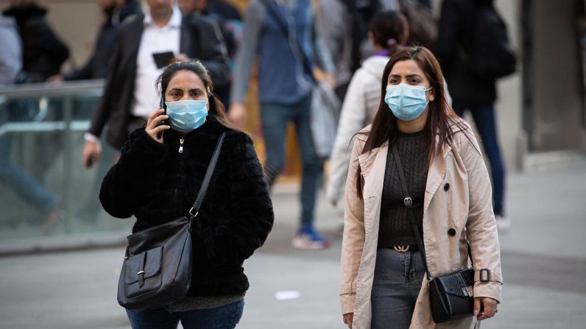 Dos mujeres con mascarillas caminando por el centro de Barcelona