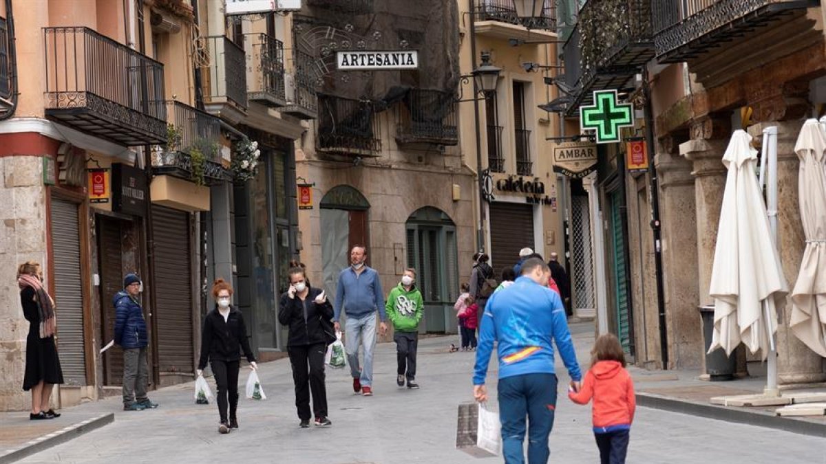 Varias personas paseando por una calle.