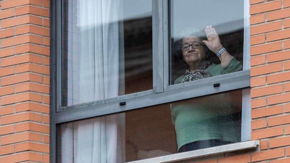 Una dona saluda des d'una residència