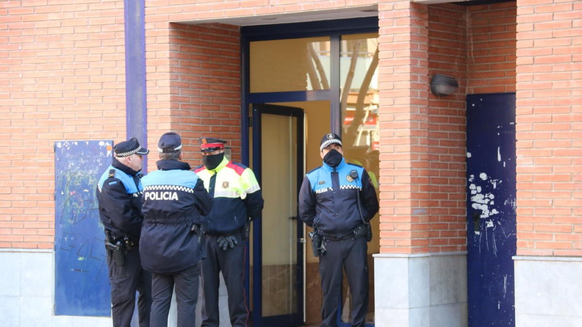 Agents de la Policia Local d'Esplugues de Llobregat i dels Mossos d'Esquadra, a la porta de l'edifici on hi ha el domicili on un home ha estat detingut acusat de matar la seva dona i la seva filla.