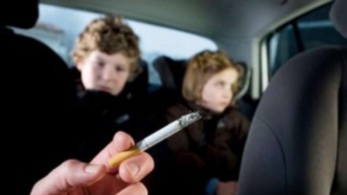 Un conductor fumant amb dos nens al darrera.