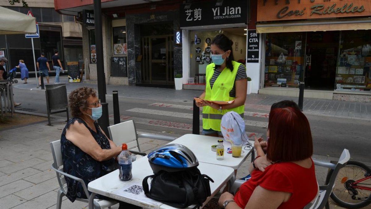 Una educadora informando a dos mujeres sentadas en una terraza de un bar de Reus.