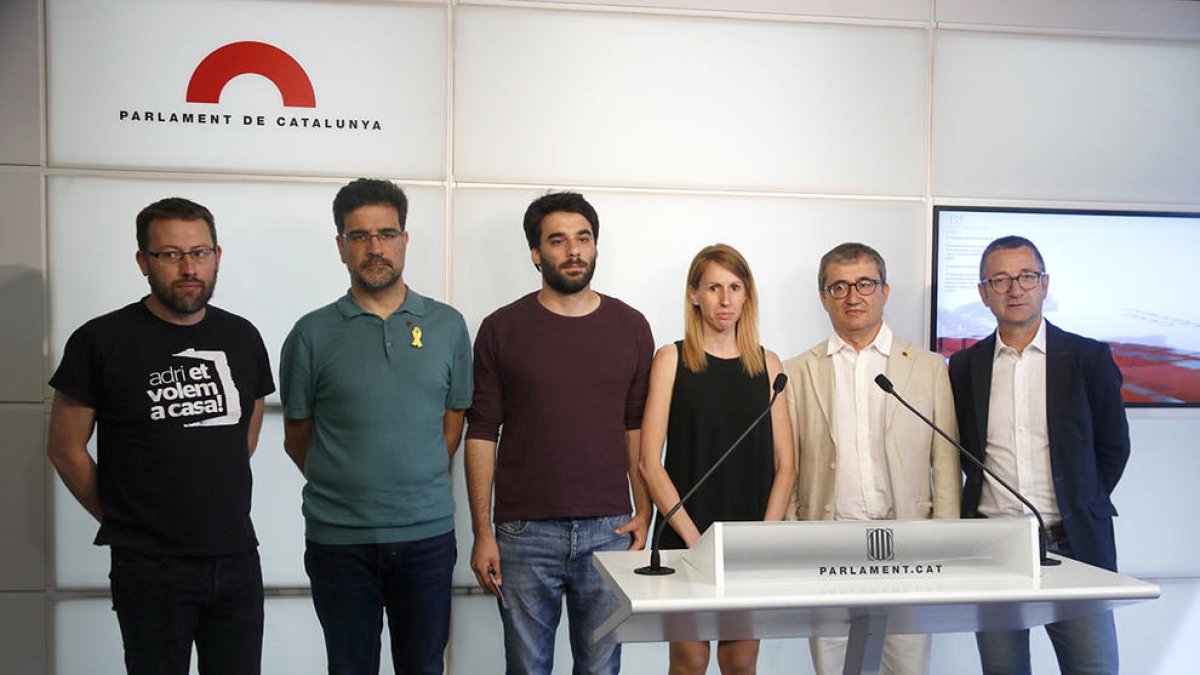 Los diputados Carles Riera (CUP), Lucas Ferro (CatECP), Jordi Terrades (PSC), Jose Rodríguez (ERC), Narcís Clara (JxCat) y la miembro de la ONG Nova Eucària Anna Carbonell en rueda de prensa en el Parlament.