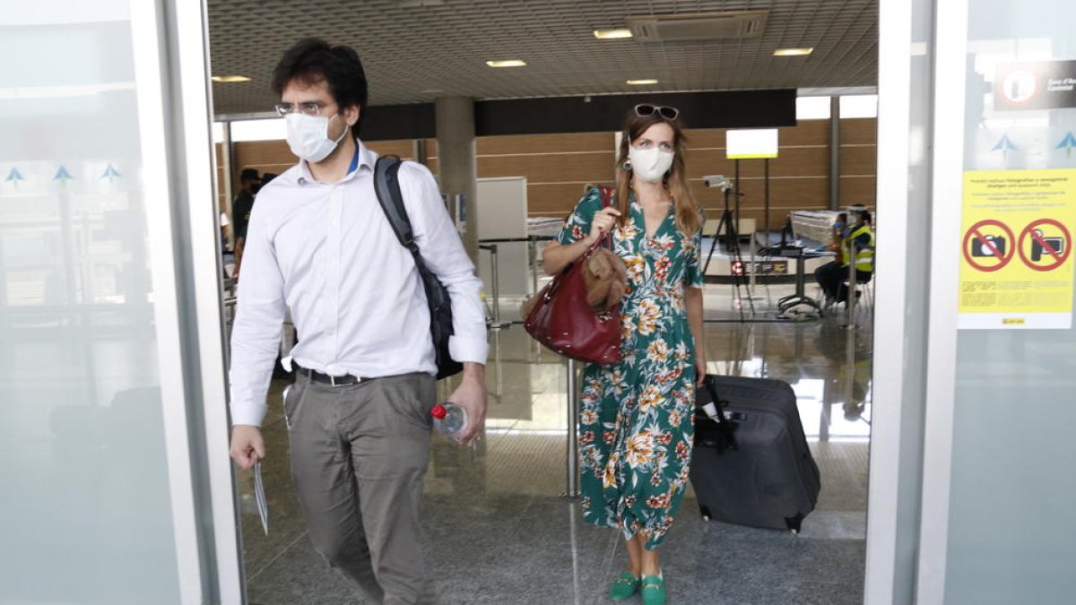 Dos passatgers amb mascareta, sortint del control de temperatura, a la terminal d'arribades de l'aeroport de Reus.
