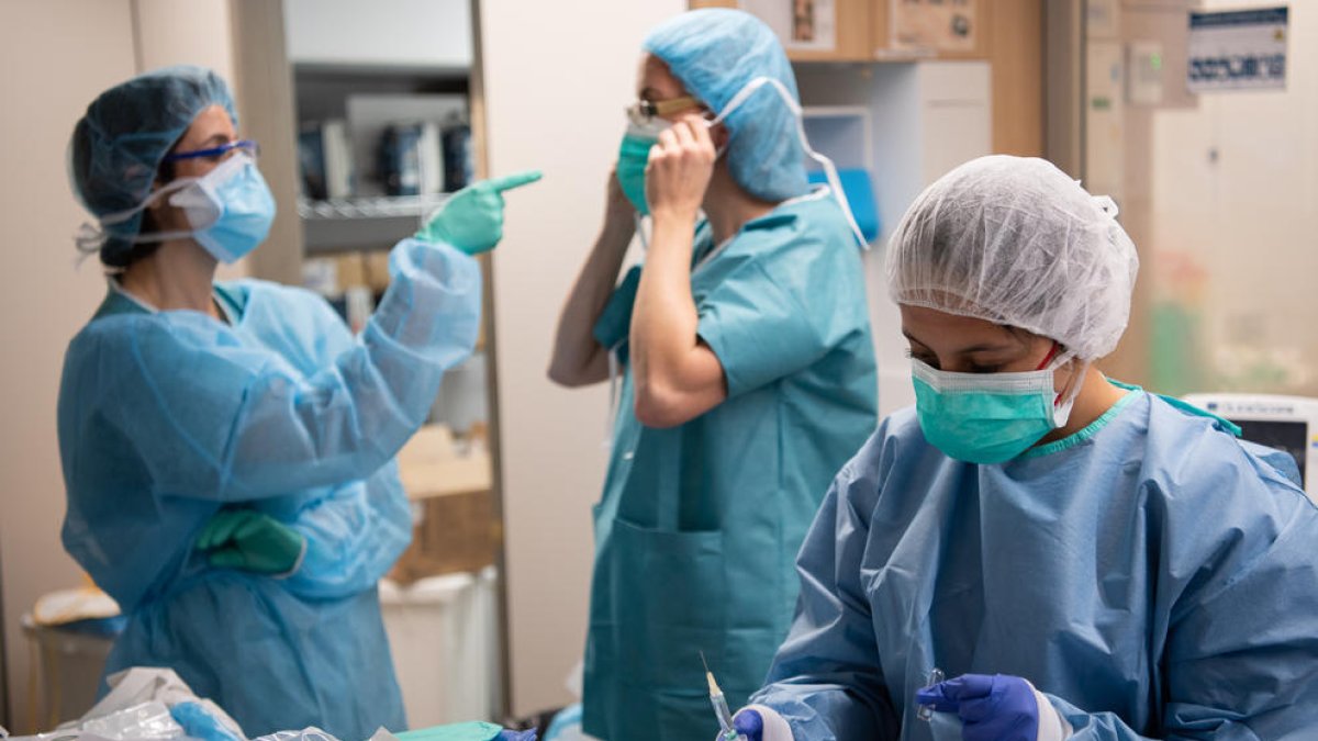 Profesionales sanitarios se protegen antes de estar en contacto con enfermos de coronavirus en el Hospital Clìnic