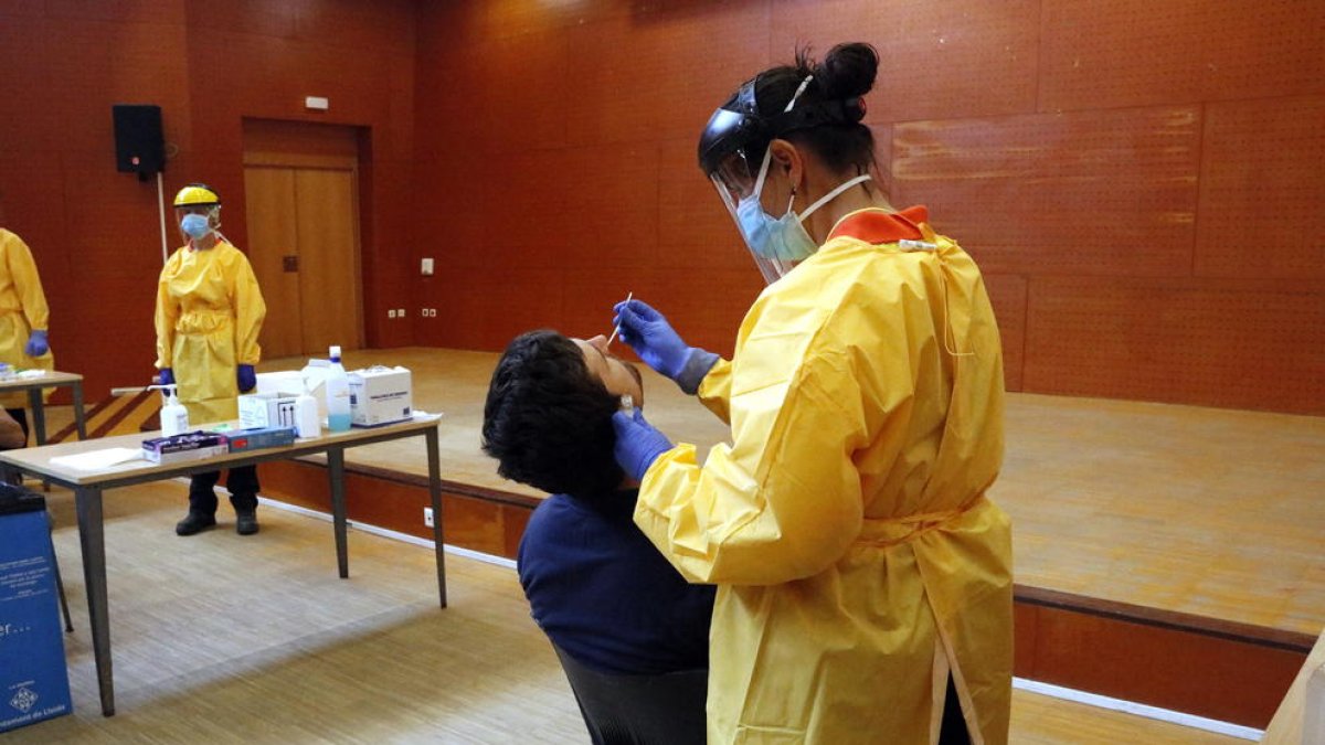 Pla obert on es pot veure un sanitari fent una prova PCR a un veí del barri de Balàfia de Lleida