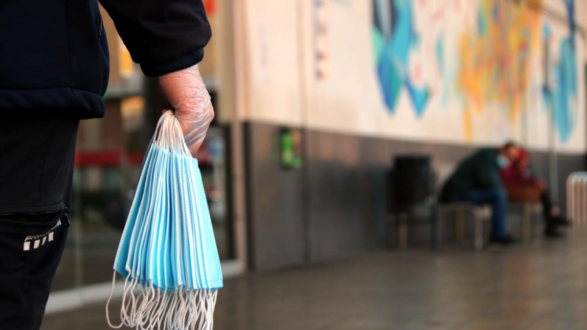 Una mà en primer pla sostenint un grapat de mascaretes a l'estació d'autobusos de Tarragona.