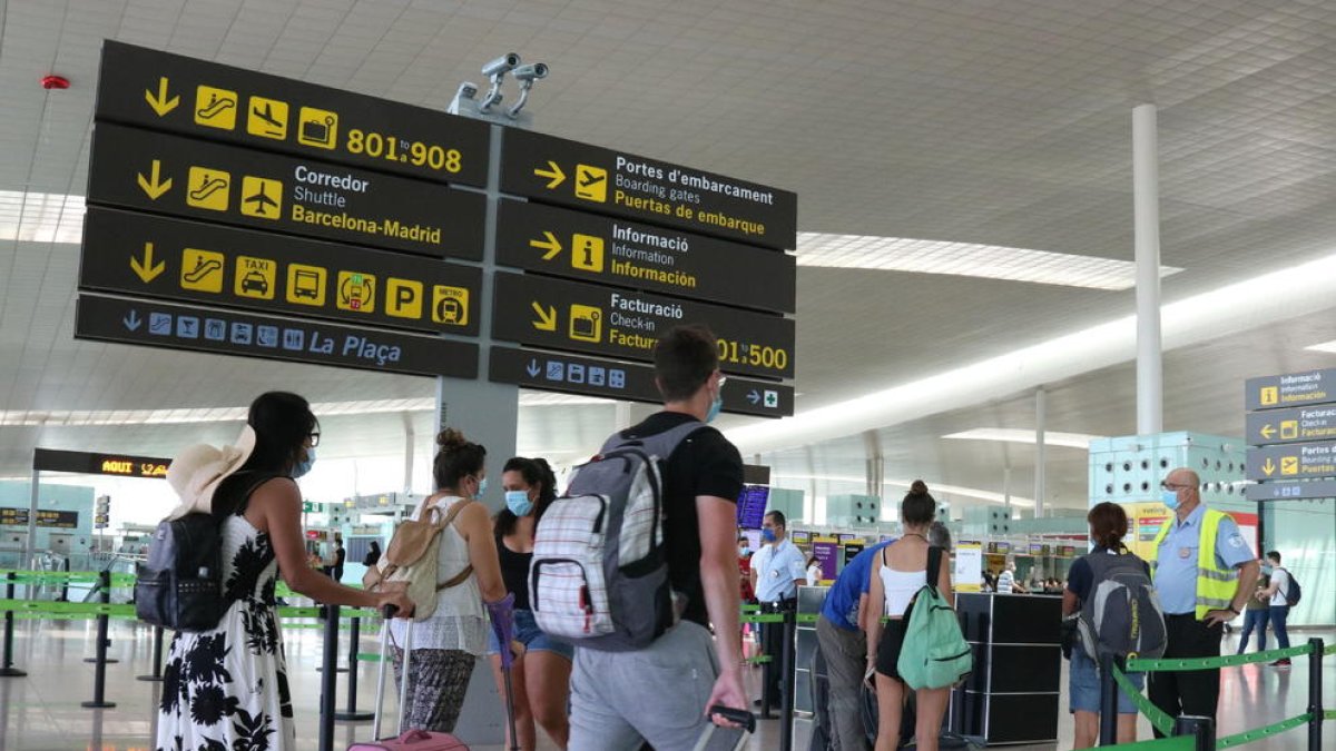 Plano general de pasajeros haciendo cola para acceder a la T1 del Aeropuerto del Prat.