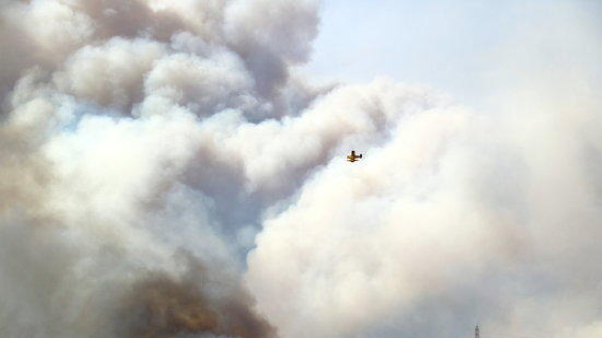 Una hidroavión sobrevuela una gran nube de humo de un incendio forestal en la Ribera d'Ebre el 26 de junio del 2019.