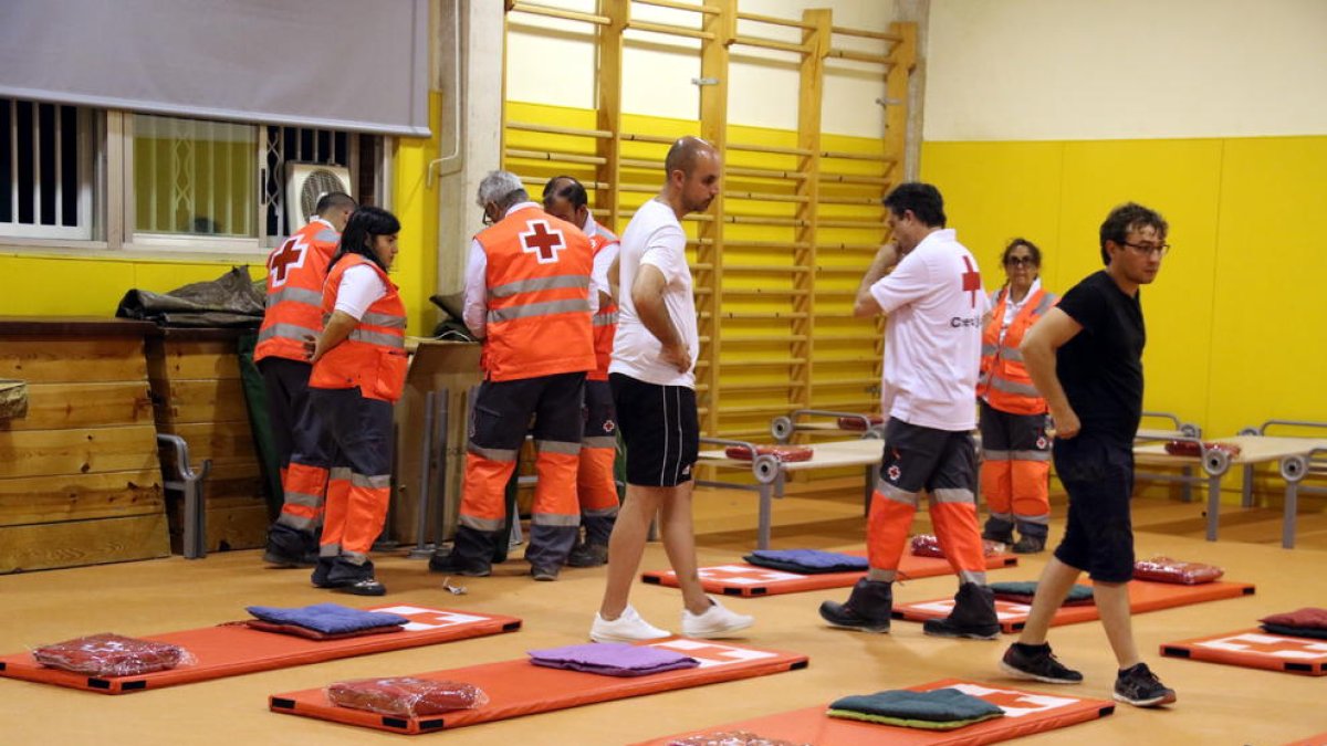 Plan|Plano general del aula deportiva de la escuela Enric Grau Fontseré de Flix con los voluntarios de Cruz Roja preparando todos los colchones y mantas para dormir los desalojados. Imagen del 27 de junio del 2019 (horizontal)