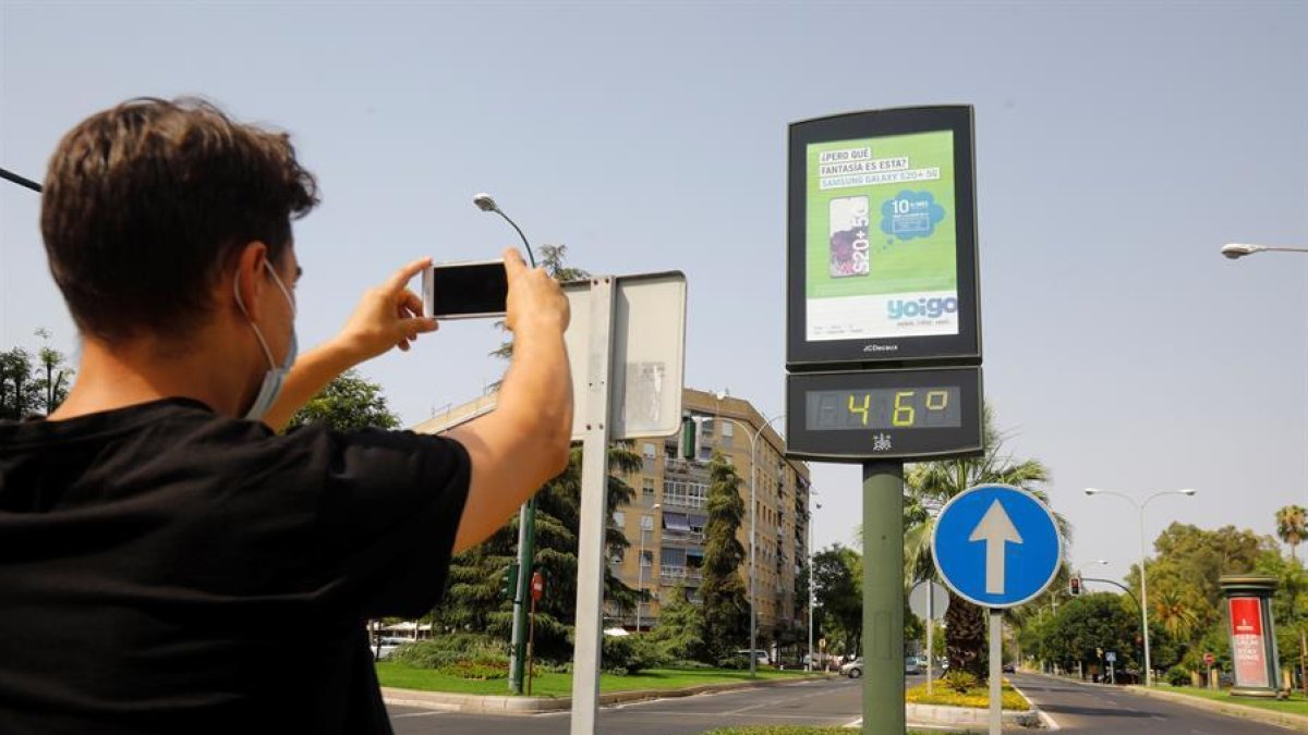 Un joven fotografía un termómetro de calle en Córdoba que marca 46 grados.
