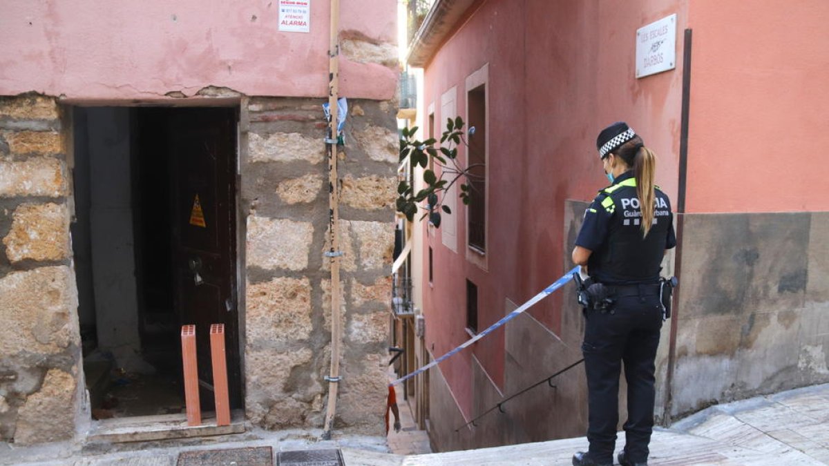 Una agent de la Guàrdia Urbana precintant l'entrada de l'edifici desallotjat a la Part Alta de Tarragona.