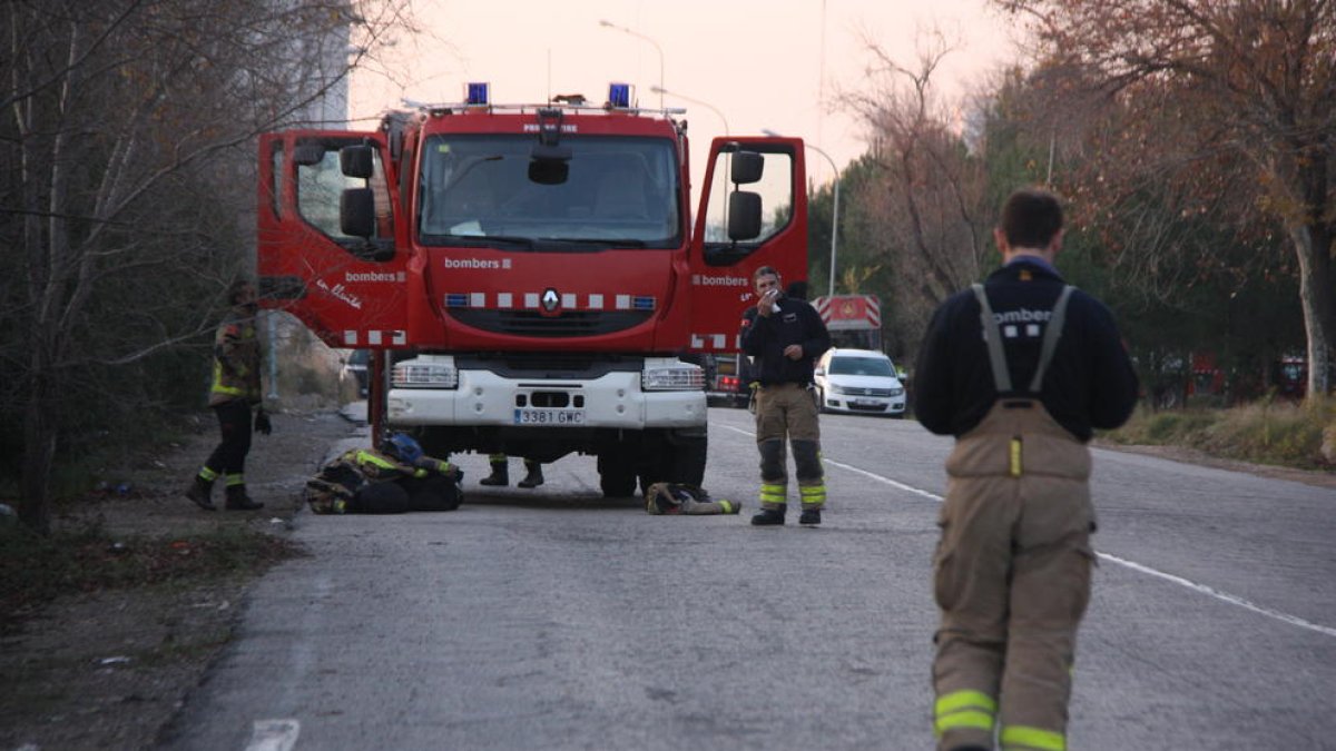 Plano general de Bombers preparando material e esperando ante|delante de uno de los camiones en el acceso de de la planta de IQOXE en la Canonja.