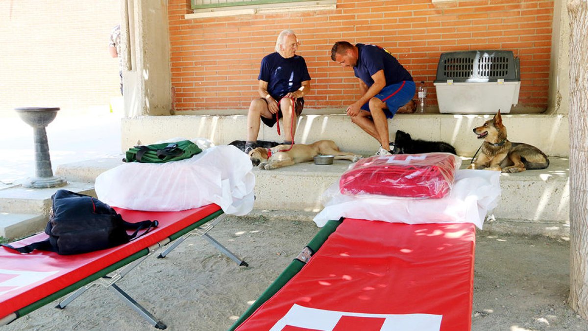 Diverses persones desallotjades, al pati de l'escola de Flix, amb diverses lliteres de la Creu Roja en primer terme.