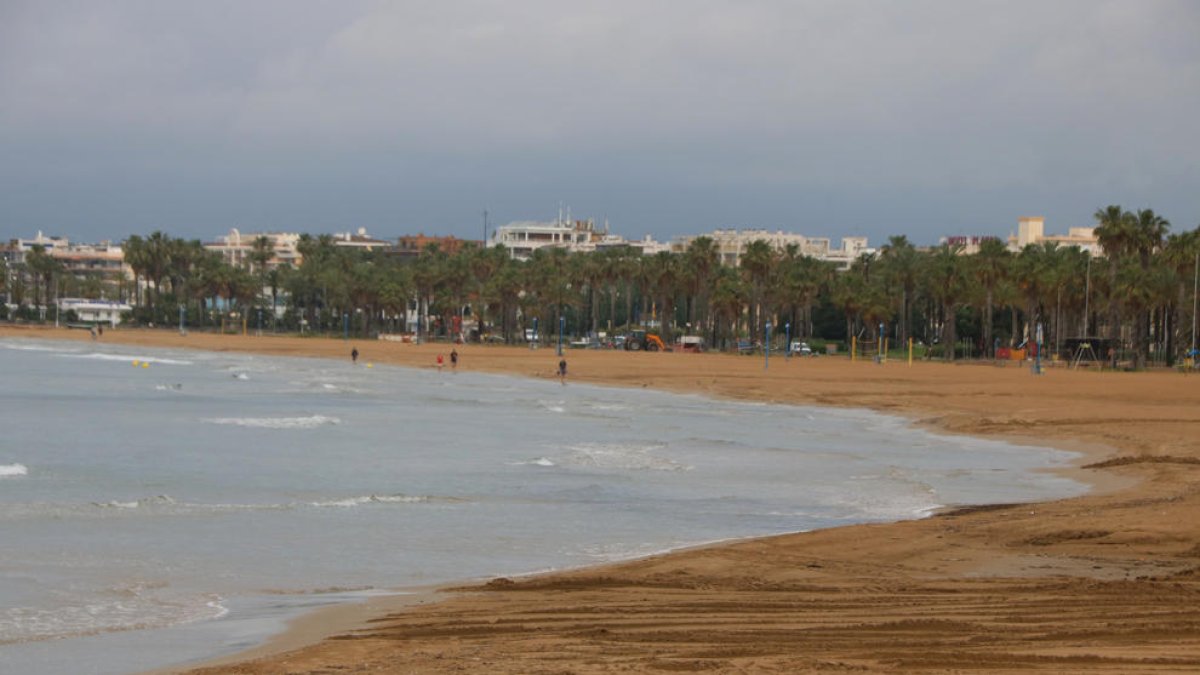La playa de Llevant de Salou con sólo algunas personas paseando cerca del mar.