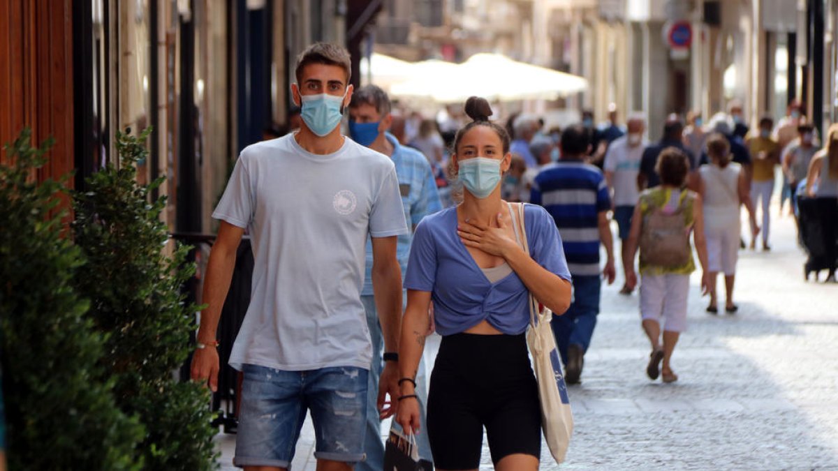 Un noi i una noia caminant amb mascareta pel carrer Monterols de Reus.