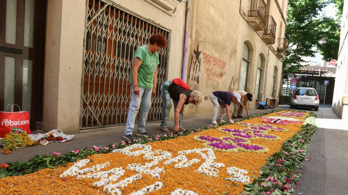 Unas mujeres montando una alfombra de flores en Valls, en motivo de la celebración del Corpus, ayer.