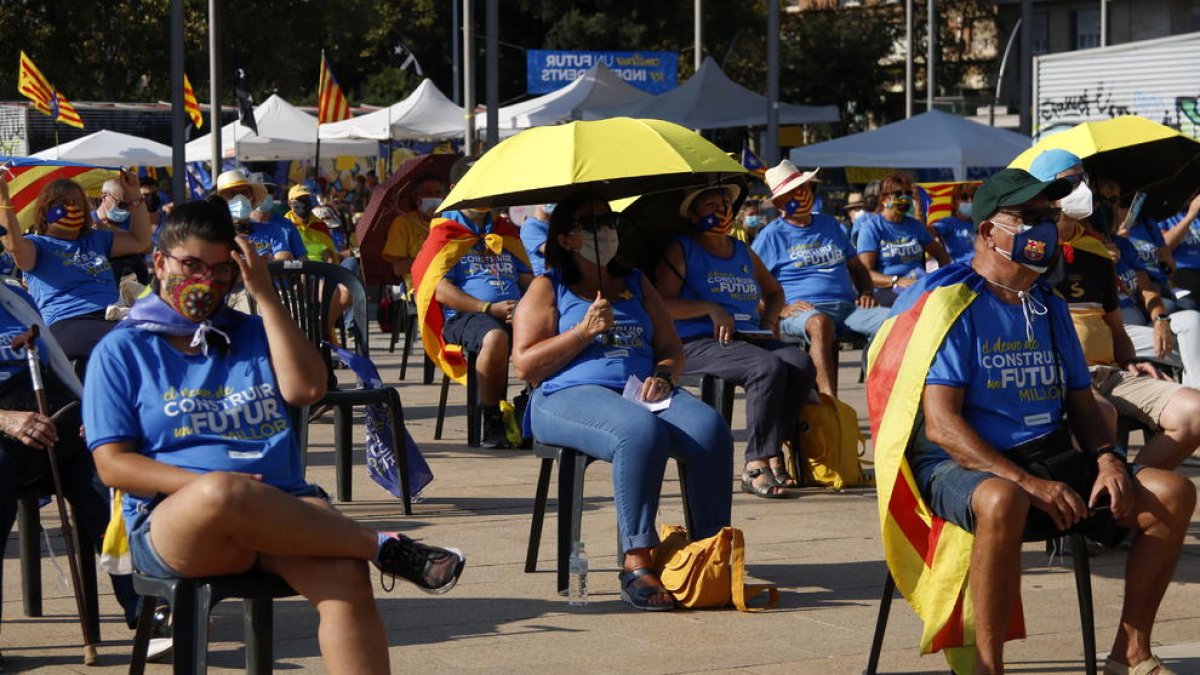 El público se protege del sol durante el acto de la ANC en motivo de la Diada en la plaza de los Países Catalanes de Barcelona.