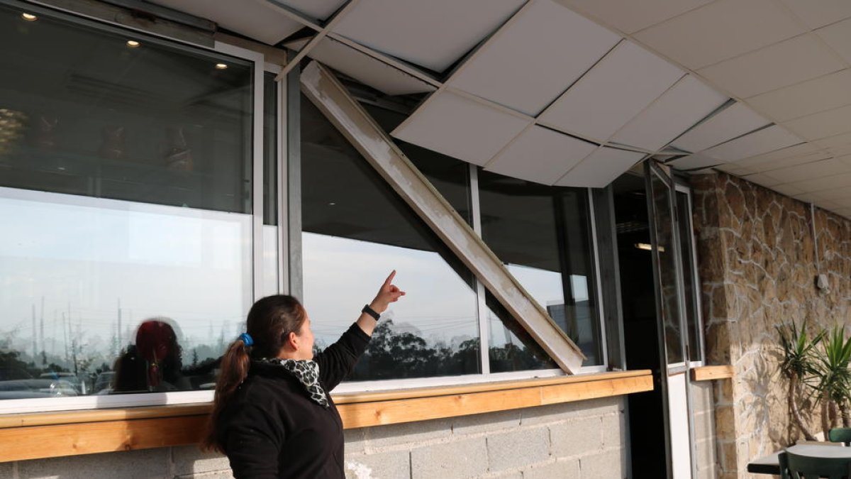 Pla general d'una treballadora mostrant els danys al sostre d'un bar de la Canonja situat a la N-340.