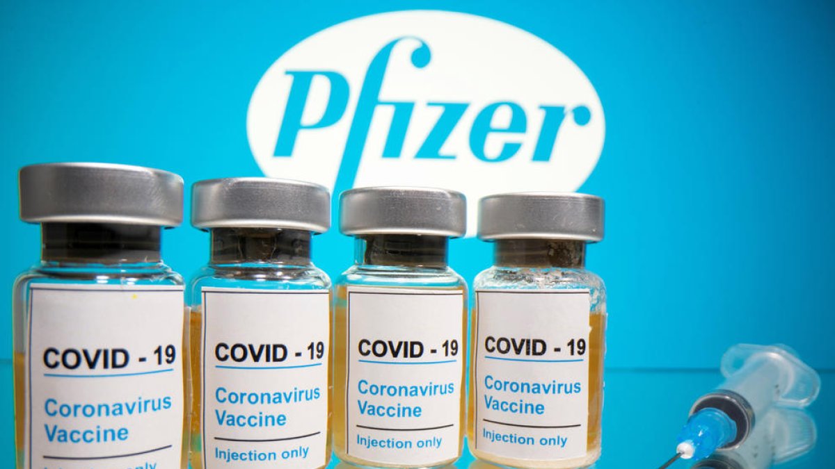 Vials amb l'etiqueta «COVID-19 / vacuna contra el coronavirus / només per injecció» i una xeringa mèdica davant del logotip de Pfizer.