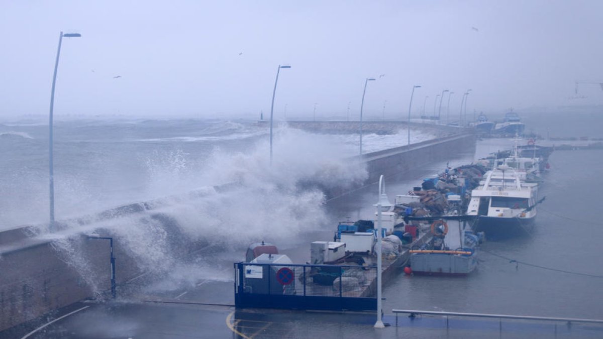 Pla general de les onades sobrepassant el moll pesquer del port de l'Ampolla.