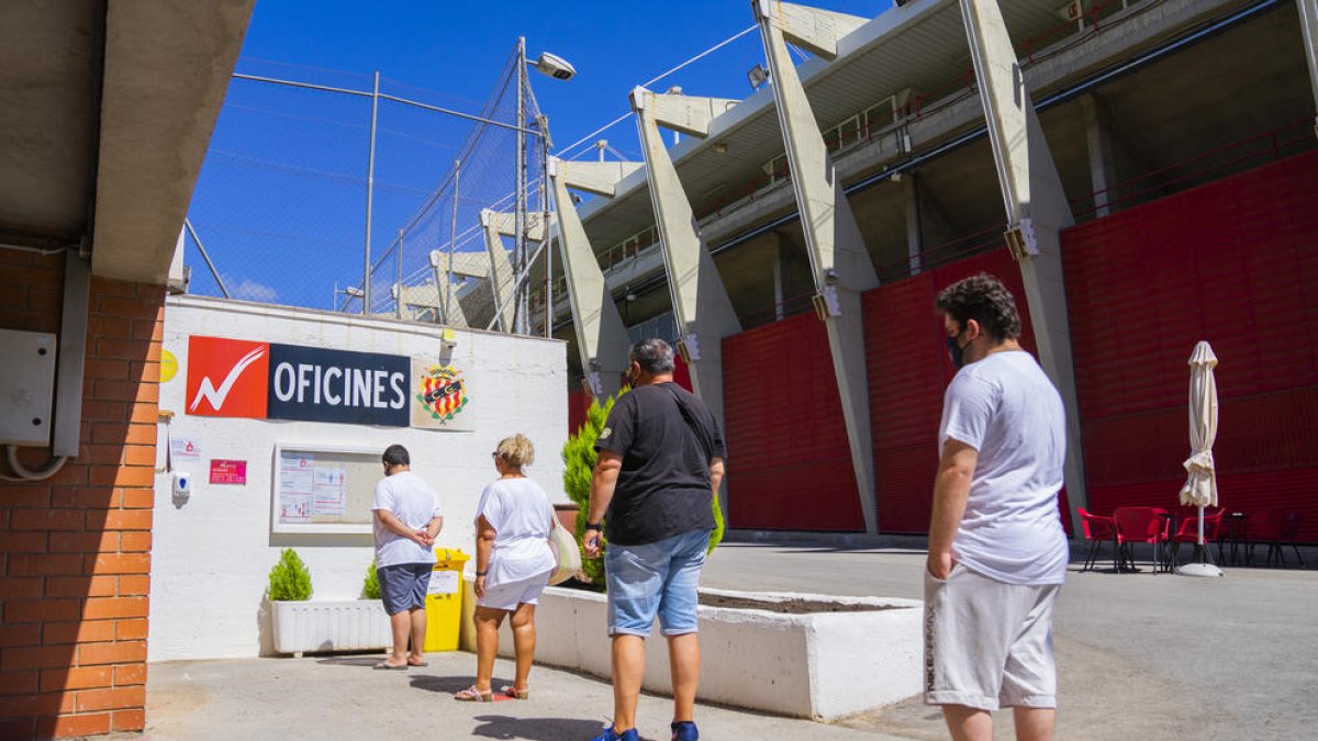 Quatre persones fan cua fora de les oficines de la Budellera esperant a recollir el seu carnet.