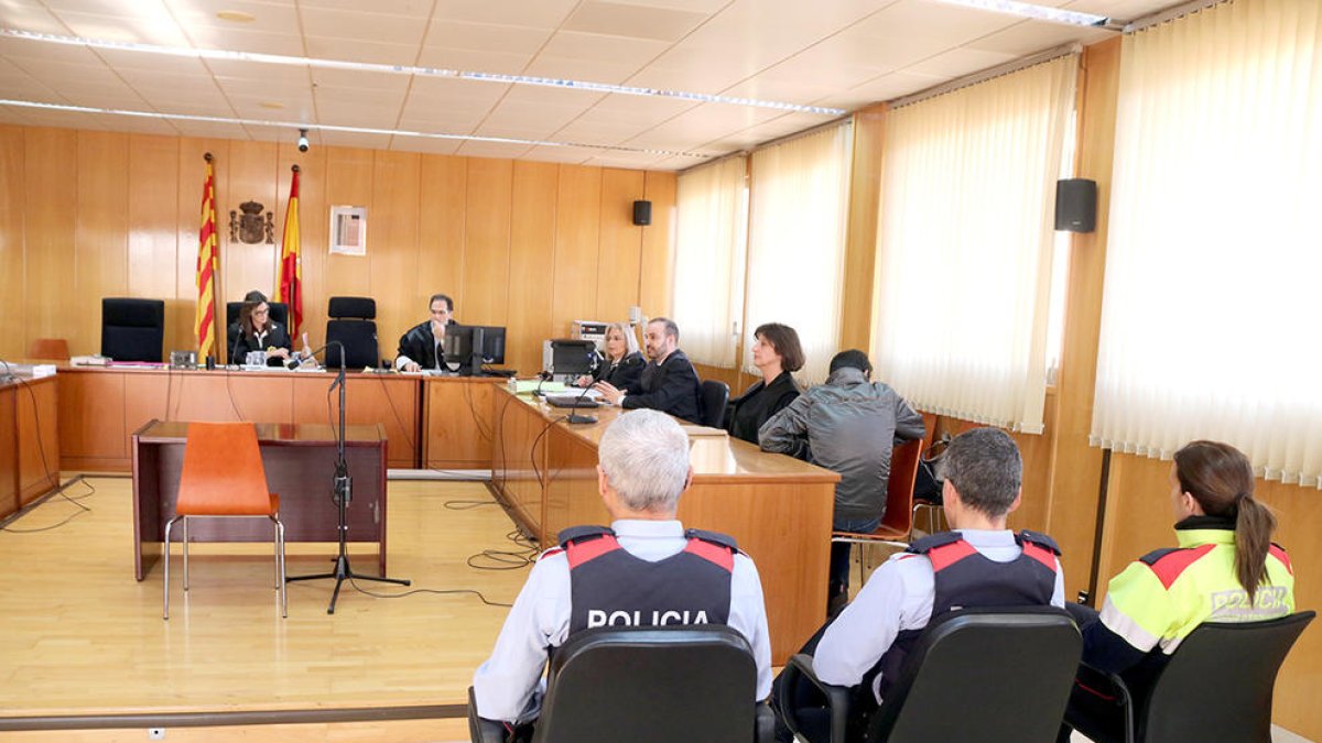 La sala de vistas de la Audiencia de Tarragona, con tres agentes de los Mossos en primer término, con el acusado sentado, de espaldas, a la derecha.