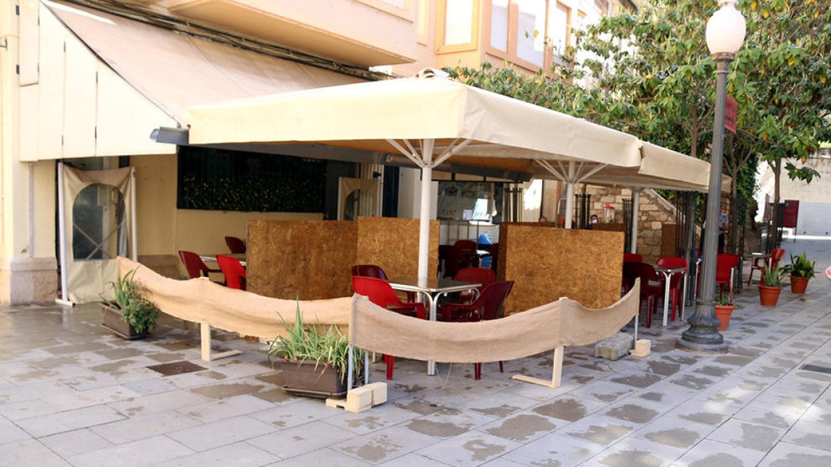 La terrassa d'un bar del centre de Tortosa amb mampares de fusta que separen les taules
