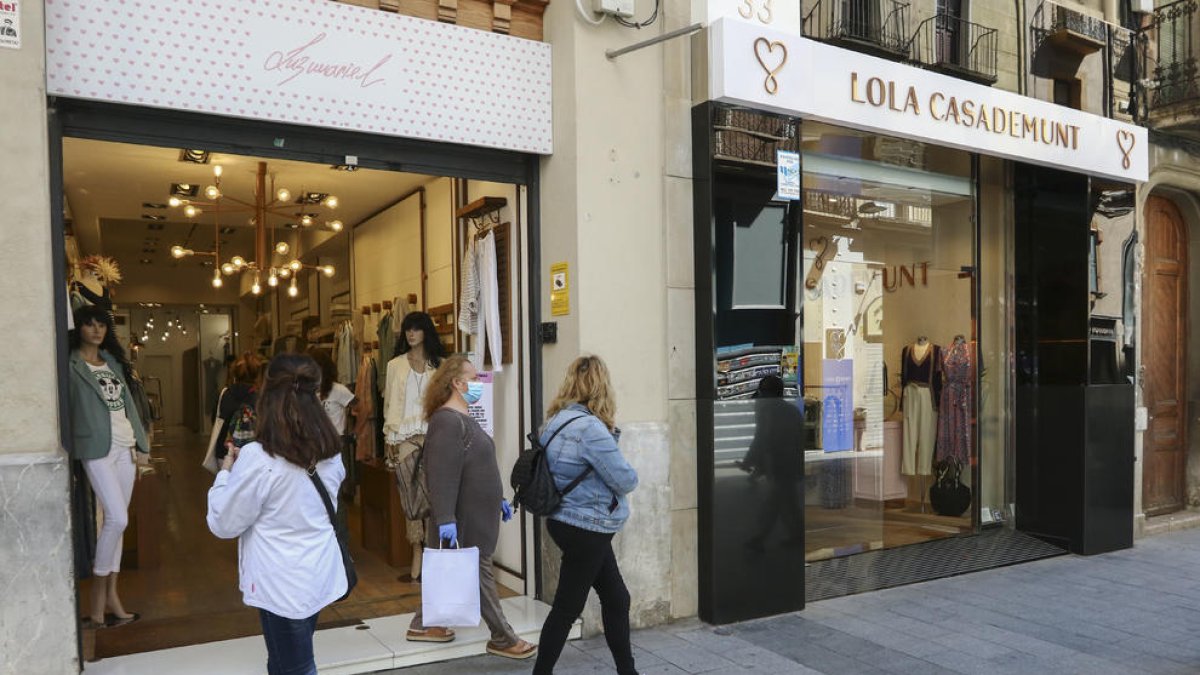 Persones andan|caminan con bolsas|bolsos por el centro de Reus.