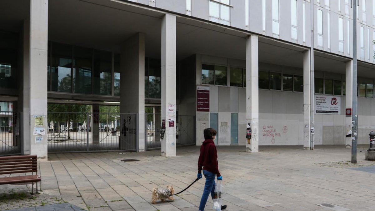 Una persona passeja un gos davant de l'accés a l'interior del Campus Catalunya tancat.