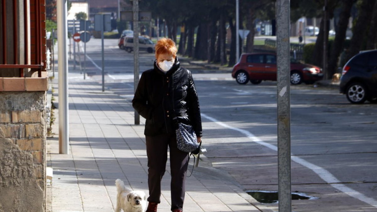 Una senyora amb màscara passejant el seu gos per l'avinguda del Canal de Mollerussa on s'hauria d'estar celebrant la Fira de Sant Josep, suspesa pel coronavirus
