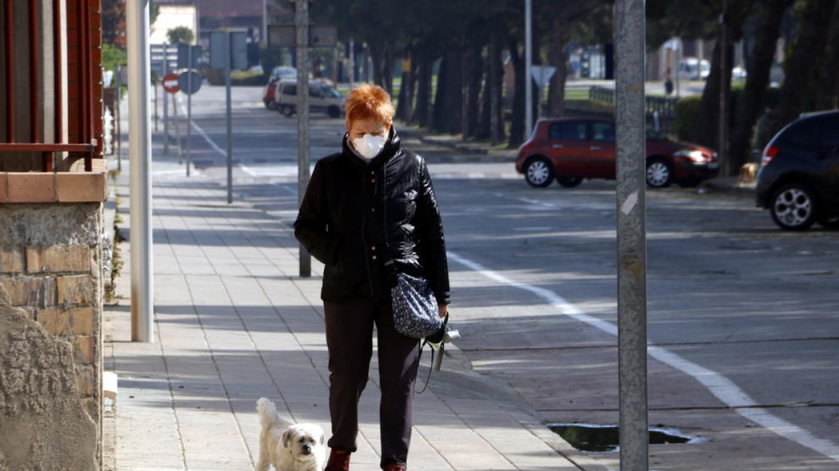 Una señora con mascarilla paseando a su perro por la avenida del Canal de Mollerussa donde se tendría que estar celebrando la Feria de Sant Josep, suspendida por el coronavirus