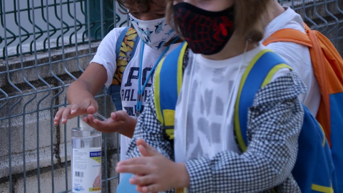 Dos alumnos de primaria lavándose las manos con gel hidroalcohólico en el acceso de la escuela Sant Llàtzer de Tortosa.