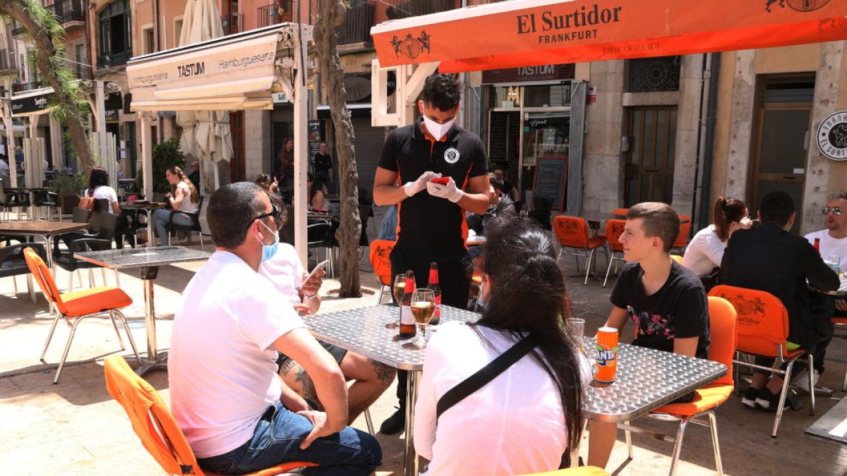 Pla obert d'un cambrer anotant la comada a uns clients en una terrassa de la plaça de la Font de Tarragona en el primer dissabte de la fase 1.