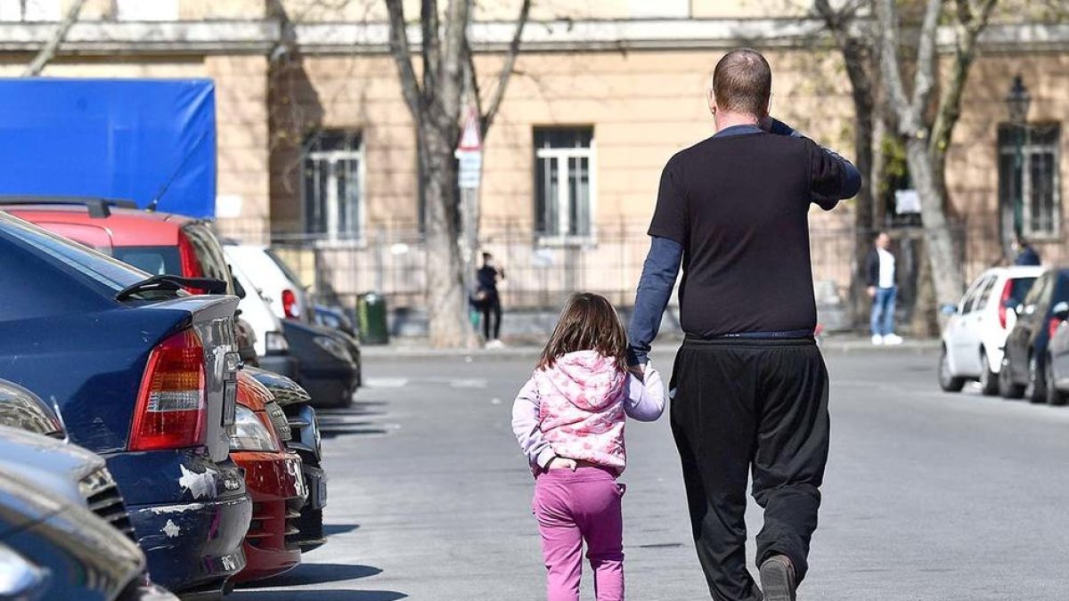 Un pare acompanya la seva filla pel carrer.