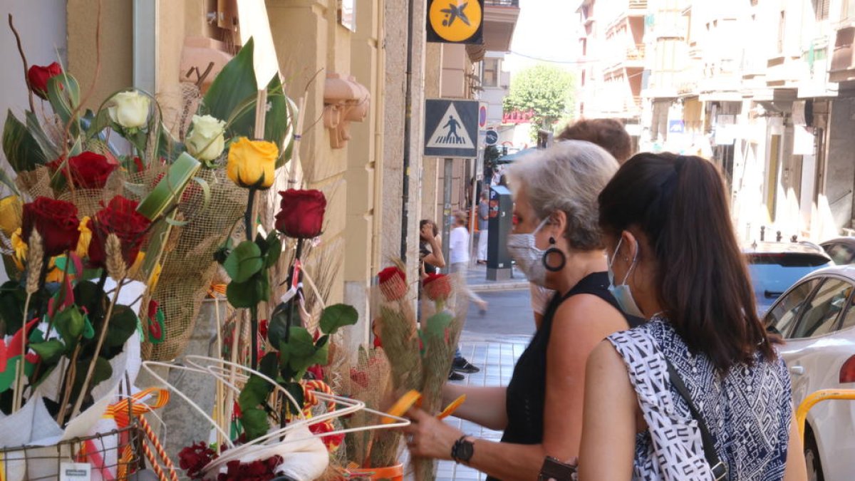 Dos jóvenes comprando rosas en la Floristería Tost de Tortosa durante el Sant Jordi de verano.