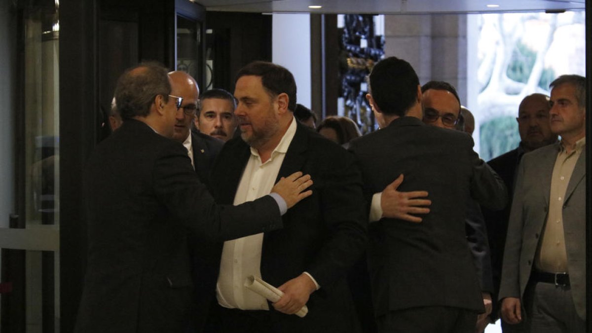 Quim Torra y Oriol Junqueras saludándose con Josep Rull y Roger Torrent abrazándose al lado, a la entrada del Parlament.