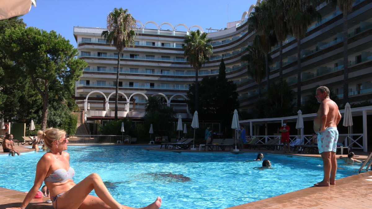 Dos turistes prenen el sol a la piscina d'un hotel de Salou.