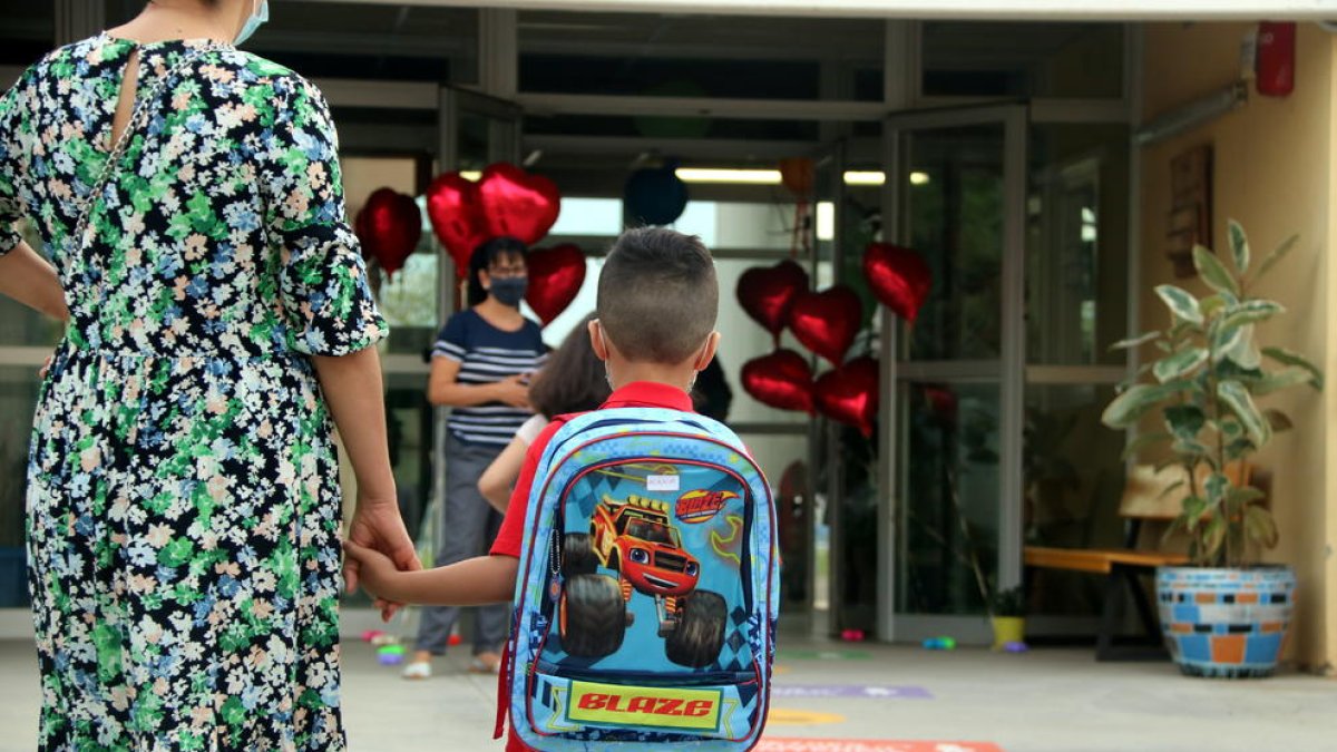 Un niño de la mano de su madre llegando a una escuela.