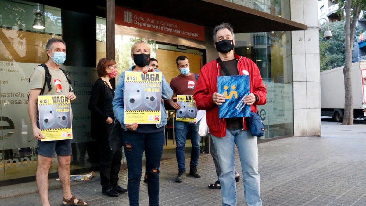 Marta Minguella, delegada de CGT Ensenyament, i Xavier Massó, secretari general de Professors de Secundària, mostren un cartell amb la convocatòria de vaga.