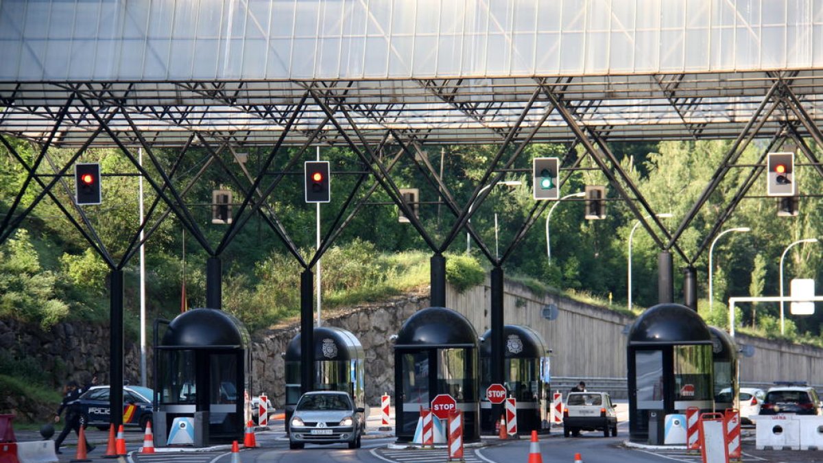 Plano de detalle de pocos vehículos entrando y saliendo del paso fronterizo que separa Andorra y Cataluña.