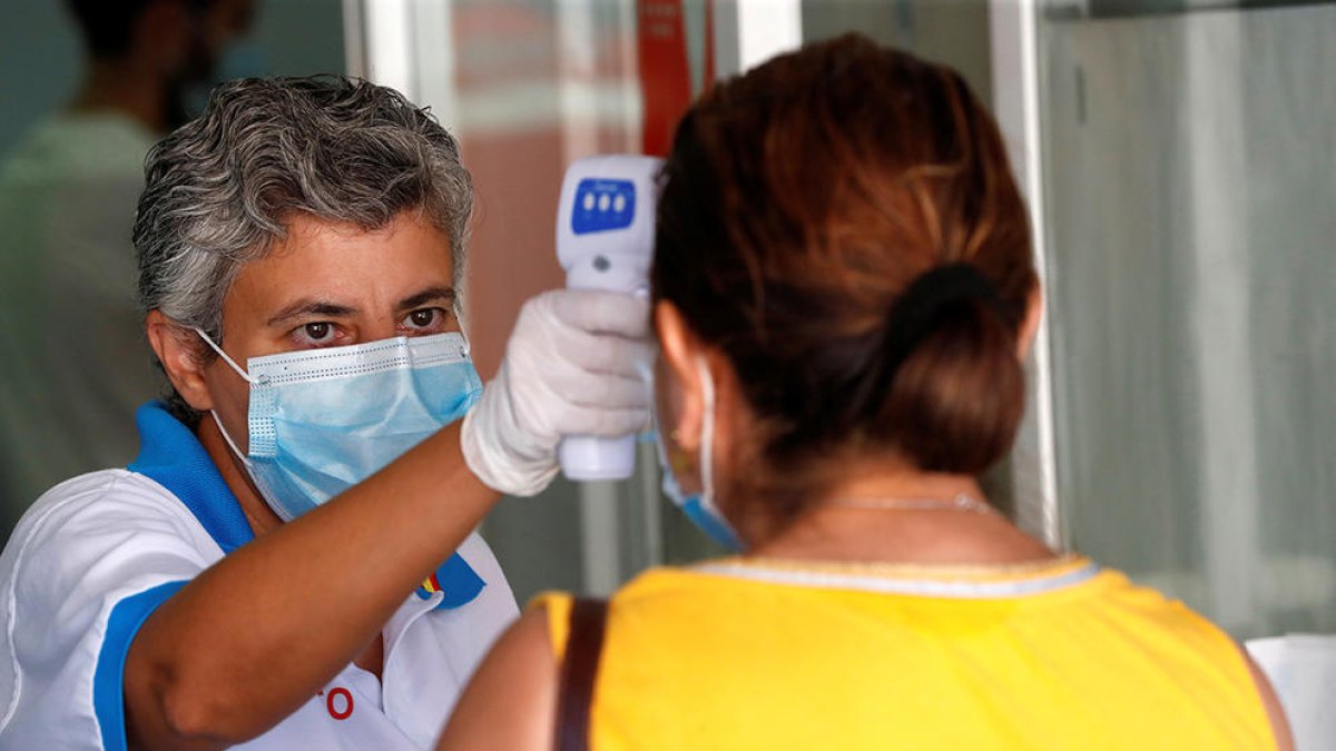 Una sanitaria comrpovant la temperatura en una usuaria en Urgencias.