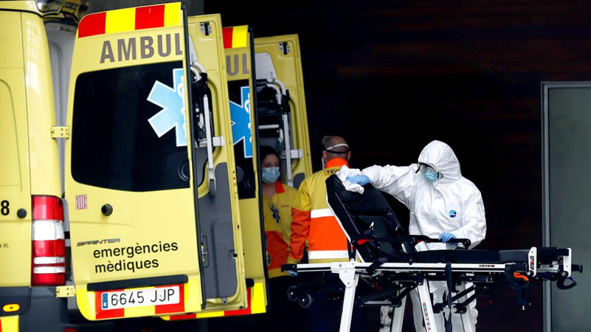 Un técnico sanitario desinfectando una litera|camilla de una ambulancia.
