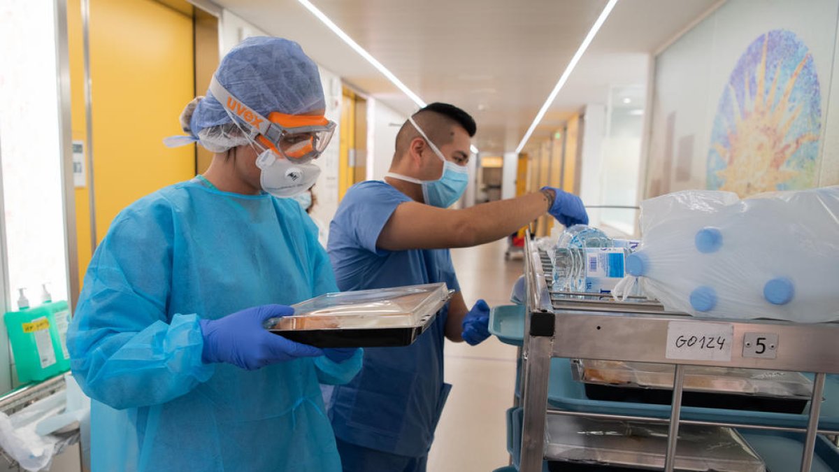 Profesionales sanitarios entran la comida a un enfermo de coronavirus del Hospital Clínic.