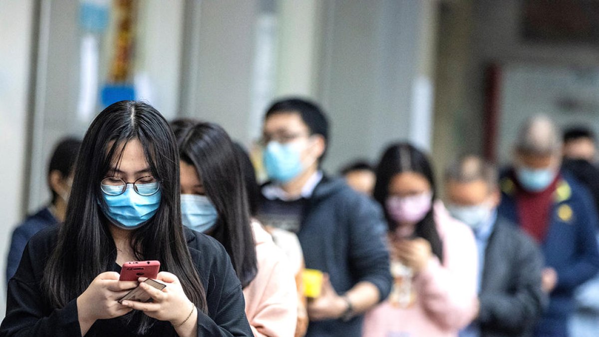Ciudadanos de Guangzhou haciendo cola para comprar mascarillas.