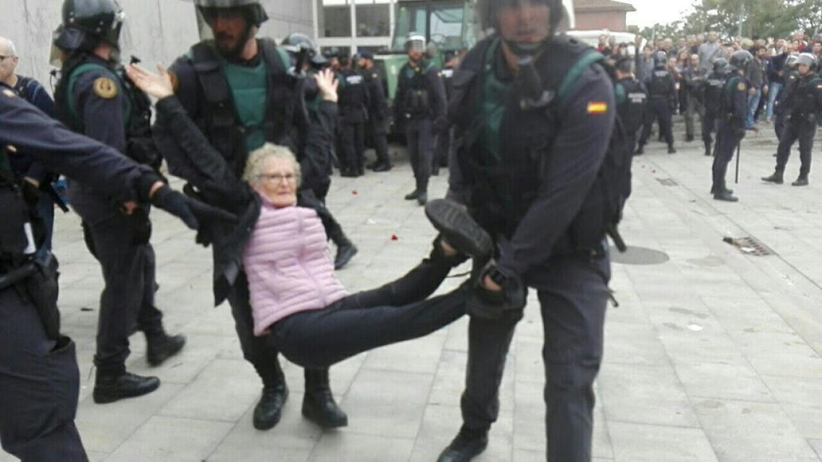 Una abuela es llevada en brazos por agentes de la Guardia Civil en el desalojo del colegio electoral de la Ràpita.