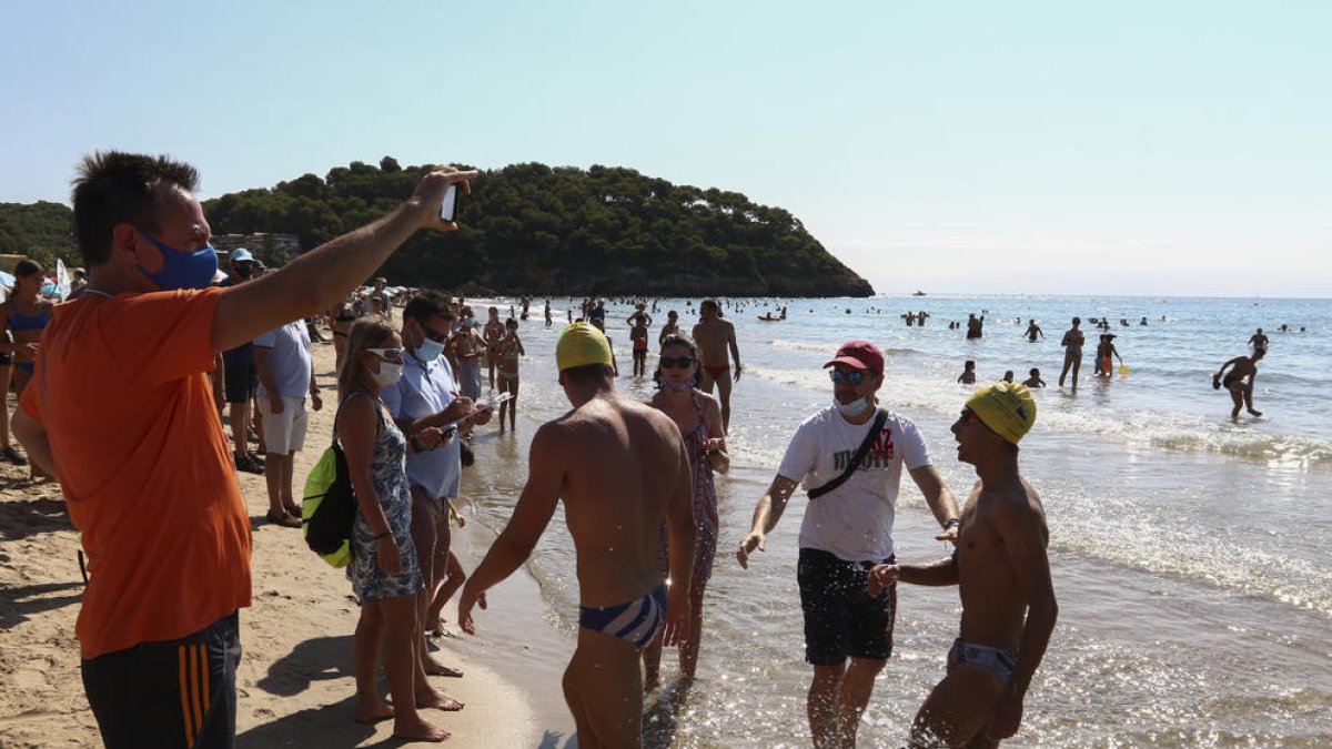 Uns nedadors són rebuts a l'arribada a la meta situada a la platja de la Móra.