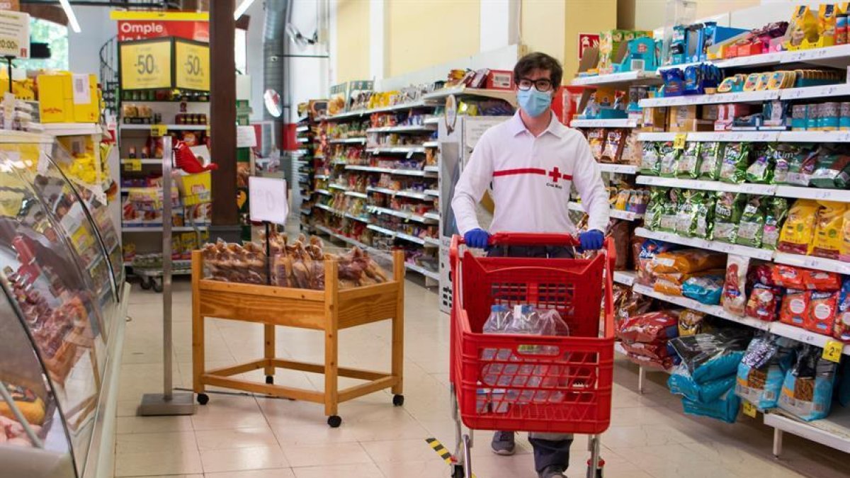 Un voluntario de la Cruz Roja hace la compra en un supermercado.