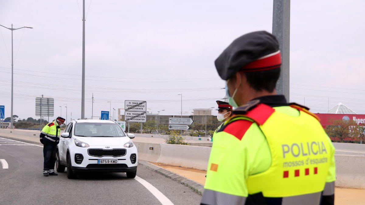 Un agente de los Mossos de Esquadra en primer término y un vehículo en el control policial de la T-11 en Tarragona.